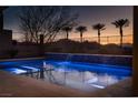 Inviting swimming pool with cascading water feature, lit up with blue lights, creating a relaxing oasis at 13 Porto Malaga St, Henderson, NV 89011