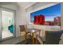 Cozy balcony seating area with a table and chairs, offering a picturesque view of the Las Vegas skyline at twilight at 2700 Las Vegas Blvd # 1301, Las Vegas, NV 89109