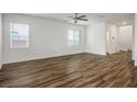 Spacious living room with wood-look flooring, neutral paint, ceiling fan, and large windows with blinds for natural light at 3909 Grazing Gazelle Ave, North Las Vegas, NV 89084
