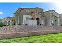 Angle view of a modern two-story house featuring neutral colors, stone accents, and rock landscaping at 534 Lassen Falls Ct, Henderson, NV 89044