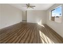 Bright living room with hardwood floors, ceiling fan, and large window letting in natural light at 6479 Gunderson Blvd, Las Vegas, NV 89103