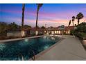 Backyard view of the swimming pool at dusk surrounded by desert landscaping and mature palm trees at 800 Kenny Way, Las Vegas, NV 89107