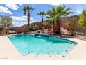Inviting backyard featuring a refreshing pool, waterfall feature, lush landscaping, and lounge chairs at 231 Pioneers Peak Ave, Henderson, NV 89002