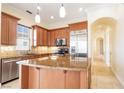 A chef's kitchen features stainless appliances, granite countertops, a center island, and tile flooring and backsplash at 26 Via Vasari # 204, Henderson, NV 89011