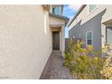 Side view of house with a walkway leading to a secure, steel door and small garden at 2720 High Echelon Rd, North Las Vegas, NV 89086