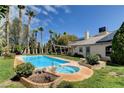 Backyard pool and spa area with lush landscaping, tall palm trees, and grass at 6513 Echo Crest Ave, Las Vegas, NV 89130