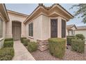 Beautiful front entrance with manicured shrubs, rock landscaping, and elegant architectural features at 10580 Riva Grande Ct, Las Vegas, NV 89135