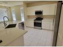 Bright kitchen featuring white cabinets, stainless steel appliances, and tile flooring at 10580 Riva Grande Ct, Las Vegas, NV 89135