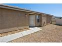 Side view of a stucco home featuring a gravel yard, concrete walkway and security door at 4016 Balsam Mountain St, Las Vegas, NV 89129