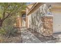 Home exterior featuring a stone facade, a beige exterior, and a manicured front yard at 1684 Flores Ln, Henderson, NV 89012
