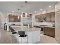Open kitchen with large island, stainless appliances, granite countertops, pendant lighting, and wood floors at 6790 Tangled Vines Ave, Las Vegas, NV 89139