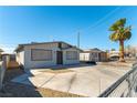 Single story home boasting a neutral toned exterior, mature landscaping and a large concrete driveway at 887 W Carey Ave, North Las Vegas, NV 89030