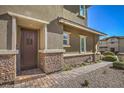 Elegant home entrance featuring a stylish wood door, stone accents, and manicured landscaping at 10398 Addie De Mar Ln, Las Vegas, NV 89135
