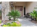 Inviting front porch featuring a cozy bench, lush greenery, and decorative door wreath at 10748 Aldrovandi Dr, Las Vegas, NV 89141