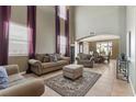 Bright living room with high ceilings, neutral walls, tile flooring, and stylish, comfortable furniture at 10748 Aldrovandi Dr, Las Vegas, NV 89141