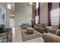 Bright living room with high ceilings, neutral walls, tile flooring, and stylish, comfortable furniture at 10748 Aldrovandi Dr, Las Vegas, NV 89141