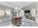 Modern kitchen with stainless steel appliances, kitchen island with barstool seating, and a cozy fireplace at 139 Serenade Ct, Henderson, NV 89074