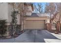 A two-car garage with a large driveway and desert landscaping located at the front of the home at 1457 Summer Glow Ave, Henderson, NV 89012