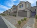 Attractive townhome row with two-car garages, desert landscaping, and a paved driveway at 3795 Canis Minor Ln # 5102, Henderson, NV 89052