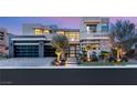 Modern home features a two-story design, decorative stone accents, glass garage door, and professional desert landscaping at 4208 Lapis Ridge Ct, Las Vegas, NV 89135