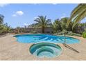 Sparkling in-ground pool with jacuzzi, concrete patio, and tropical palm trees creates a backyard oasis for relaxation at 4343 Sharpshooter Ln, North Las Vegas, NV 89031