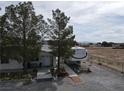 Street view of single story home, long driveway, desert landscaping and mature trees at 4861 Pahrump Valley Blvd, Pahrump, NV 89048