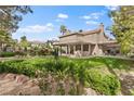Large backyard featuring lush grass, a covered patio, mature trees, and tasteful landscaping for outdoor enjoyment at 5205 Sandy Cactus Ln, Las Vegas, NV 89149