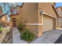 Side view of a two-story tan home with a two car garage and landscaped entry way at 6217 Red Jamboree Ct, Las Vegas, NV 89130
