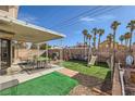 Outdoor area with a covered patio, lush turf, a playset, and mature palm trees at 6982 Rusty Nail Way, Las Vegas, NV 89119