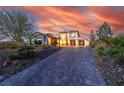 Elegant two-story home with a paver driveway and beautiful landscaping at sunset at 18 Grand Corniche Dr, Henderson, NV 89011