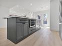 Kitchen island with gray cabinetry, quartz countertop, stainless steel microwave and an open concept design at 2894 Matese Dr, Henderson, NV 89052
