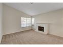 Bright and cozy living room featuring a brick fireplace, a large window, and neutral carpet at 3667 Edinburgh Dr, Las Vegas, NV 89103