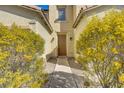 A charming front entryway with a wooden door, framed by vibrant, mature landscaping at 5948 Sakhalin Ave, Las Vegas, NV 89139
