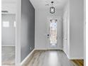 Bright foyer featuring wood-look floors, decorative front door with glass accents, and light gray accent wall at 783 Hibiscuss Blossom St, Henderson, NV 89011