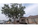 Angle shot of a cozy home with a mature tree providing shade and charm to the facade at 1910 Hoover St, North Las Vegas, NV 89030