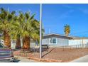 View of front yard with mature trees, rock ground cover and a single story home with fence at 2450 Tournament St, Las Vegas, NV 89142