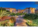 Inviting single-story home with stone accents, lush landscaping and manicured front yard at dusk at 2872 Sumter Valley Cir, Henderson, NV 89052