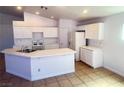 Bright kitchen featuring an island, white cabinets, and updated appliances at 3433 Nebaum Ct, North Las Vegas, NV 89032