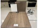 An interior design sample board displays luxury vinyl plank, quartz countertop, sleek bath faucet, and cabinet finishes at 9241 Soho Sky Ct, Las Vegas, NV 89148