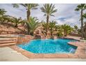 Backyard oasis with a sparkling pool, waterfall feature, palm trees, and lush landscaping at 1304 Husson Ct, Las Vegas, NV 89142