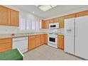 Bright kitchen with white appliances, wood cabinets, and a tiled floor, creating a clean and functional space at 2608 Saltbush Dr, Las Vegas, NV 89134