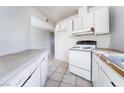 Functional kitchen featuring tile floors, white cabinets, and a white oven at 3704 Haddock Ave, North Las Vegas, NV 89030