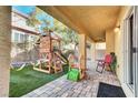 Covered patio and backyard with a play structure, perfect for outdoor entertainment and recreation at 8456 Blackstone Ridge Ct, Las Vegas, NV 89139