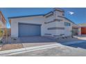 A modern home featuring a two car garage, gray door, and desert landscaping at 990 Golden Summit Dr, Las Vegas, NV 89138