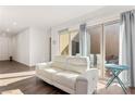 Cozy living room with a white leather sofa, tiled flooring, and sliding doors leading to the outdoor space at 10879 Artesano Ave, Las Vegas, NV 89135