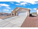 A single-story home with a large driveway and a two-car garage, with low maintenance desert landscaping at 2419 Country Orchard St, North Las Vegas, NV 89030