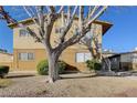 Exterior view of tan two-story apartment building with a tree in the front yard at 3821 1/2 Daisy St # 25, Las Vegas, NV 89119