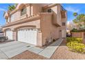 Side view of townhome showcasing a tile roof, two-car garage, pedestrian gate, and desert landscaping at 5382 Runningbrook Rd, Las Vegas, NV 89120