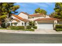 View of exterior elevation with clay tile roof, two-car garage and mature trees at 6923 Emerald Springs Ln, Las Vegas, NV 89113