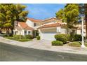 Charming exterior featuring a clay tile roof, two-car garage, and lush, mature trees at 6923 Emerald Springs Ln, Las Vegas, NV 89113
